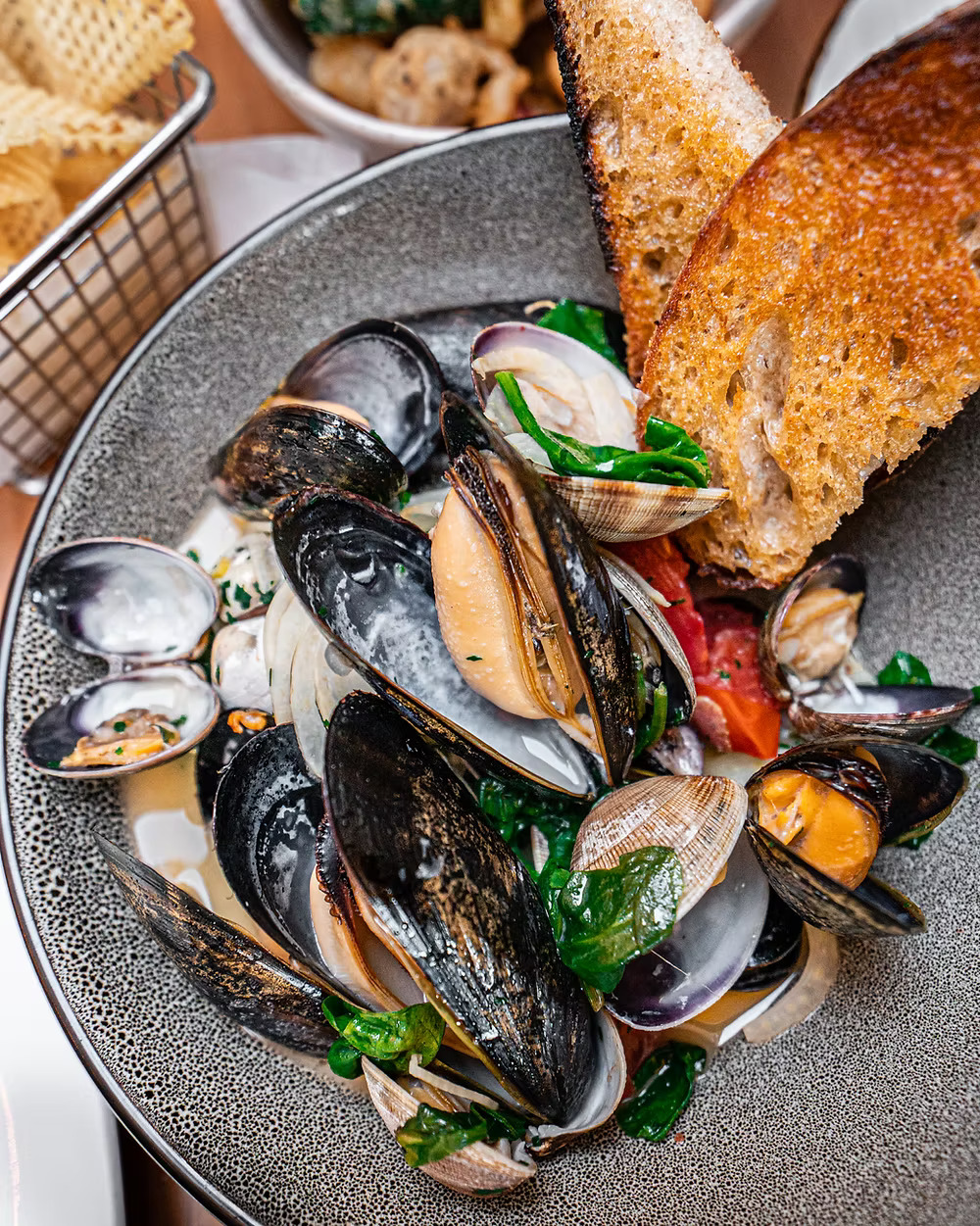 A bowl of steaming mussels and clams